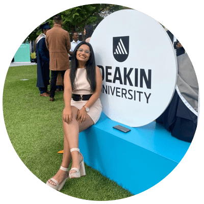 a woman posing in front of a sign that says keakin university.